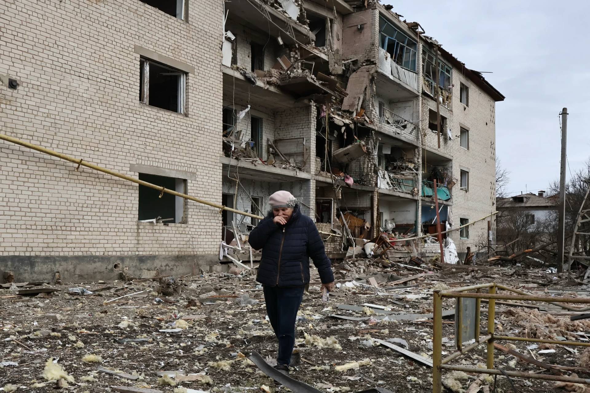 In this photo provided by Ukraine’s 65th Mechanized Brigade press service, a local passes by a destroyed apartment building following an Russian air strike in the town of Komyshuvakha in the Zaporizhzhia region of Ukraine, Friday, Feb. 20, 2026. (Credit: Andriy Andriyenko/Ukraine’s 65th Mechanized Brigade via AP.)