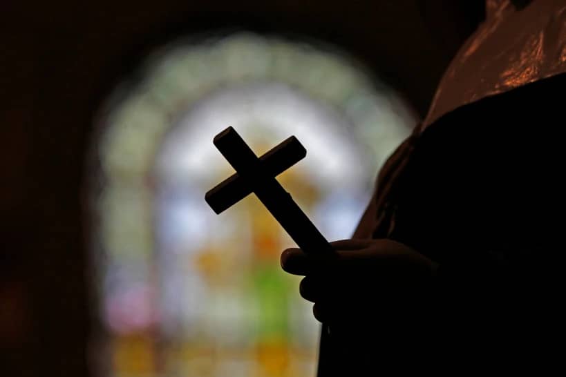 A cross is silhouetted against a stained glass window inside a Catholic Church in New Orleans on Dec. 1, 2012. (Credit: Gerald Herbert/AP.)