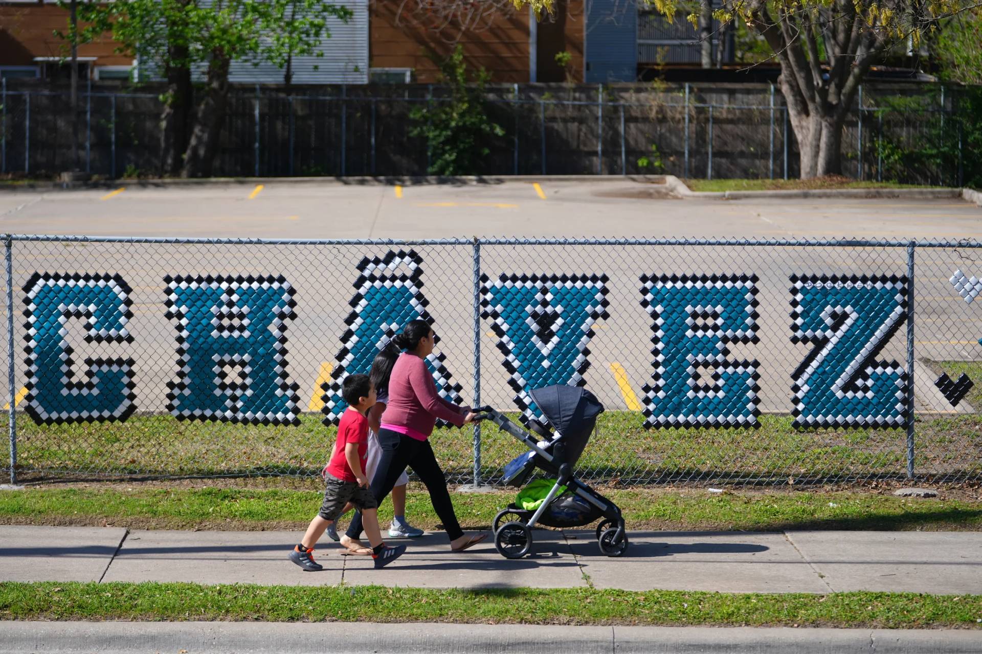 Pedestrians walk past the parking lot of the Cesar Chavez Learning Center in Dallas, Thursday, March 19, 2026. (Credit: Julio Cortez/AP.)