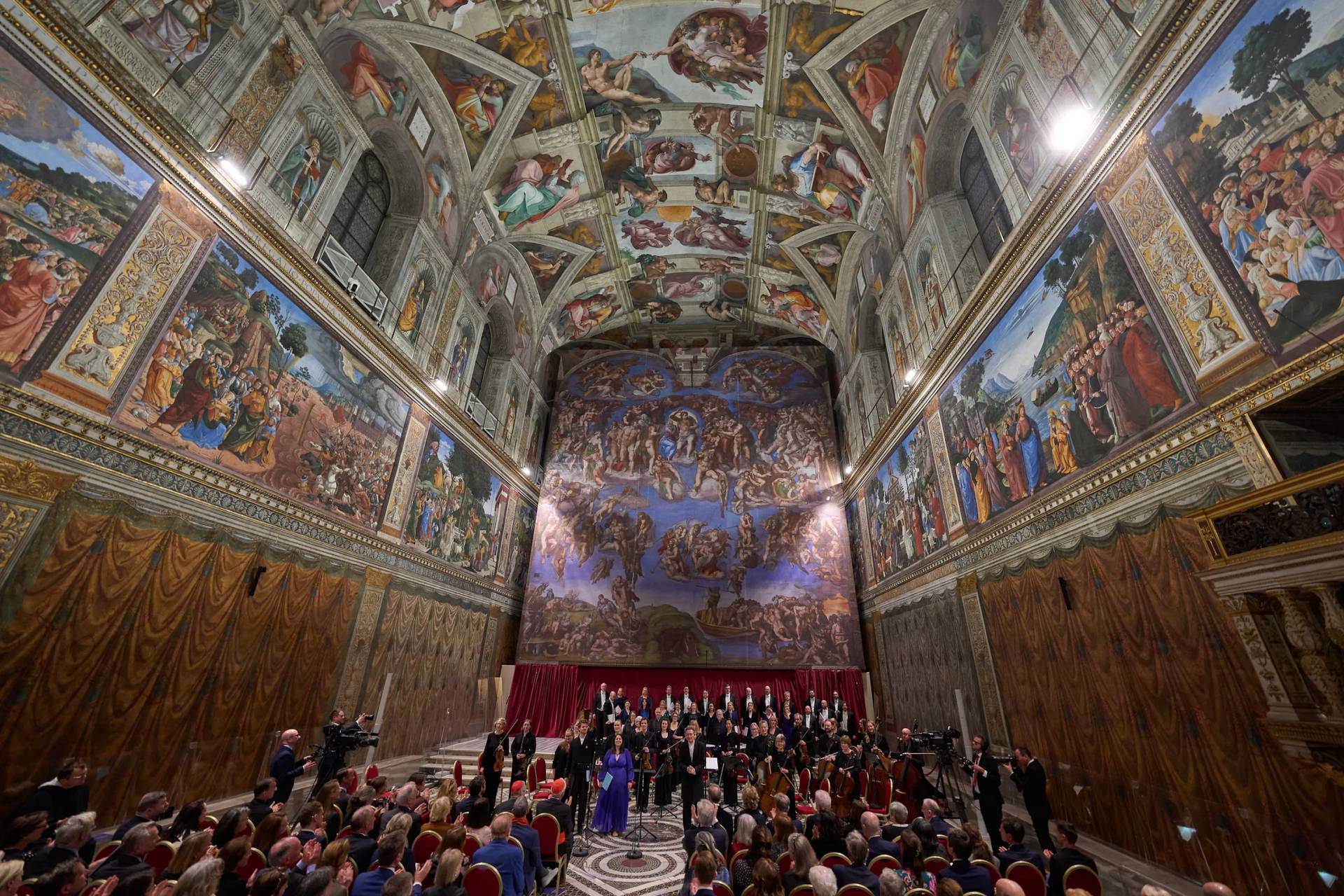 Conductor Harry Christopher, center, with tenor Matthew McKinney, left, soprano Elizabeth Watts, second from left, and The Sixteen present Angels Unawares byJames MacMillan in the Sistine Chapel at the Vatican, Sunday, March 22, 2026. (Credit: Domenico Stinellis/AP.)