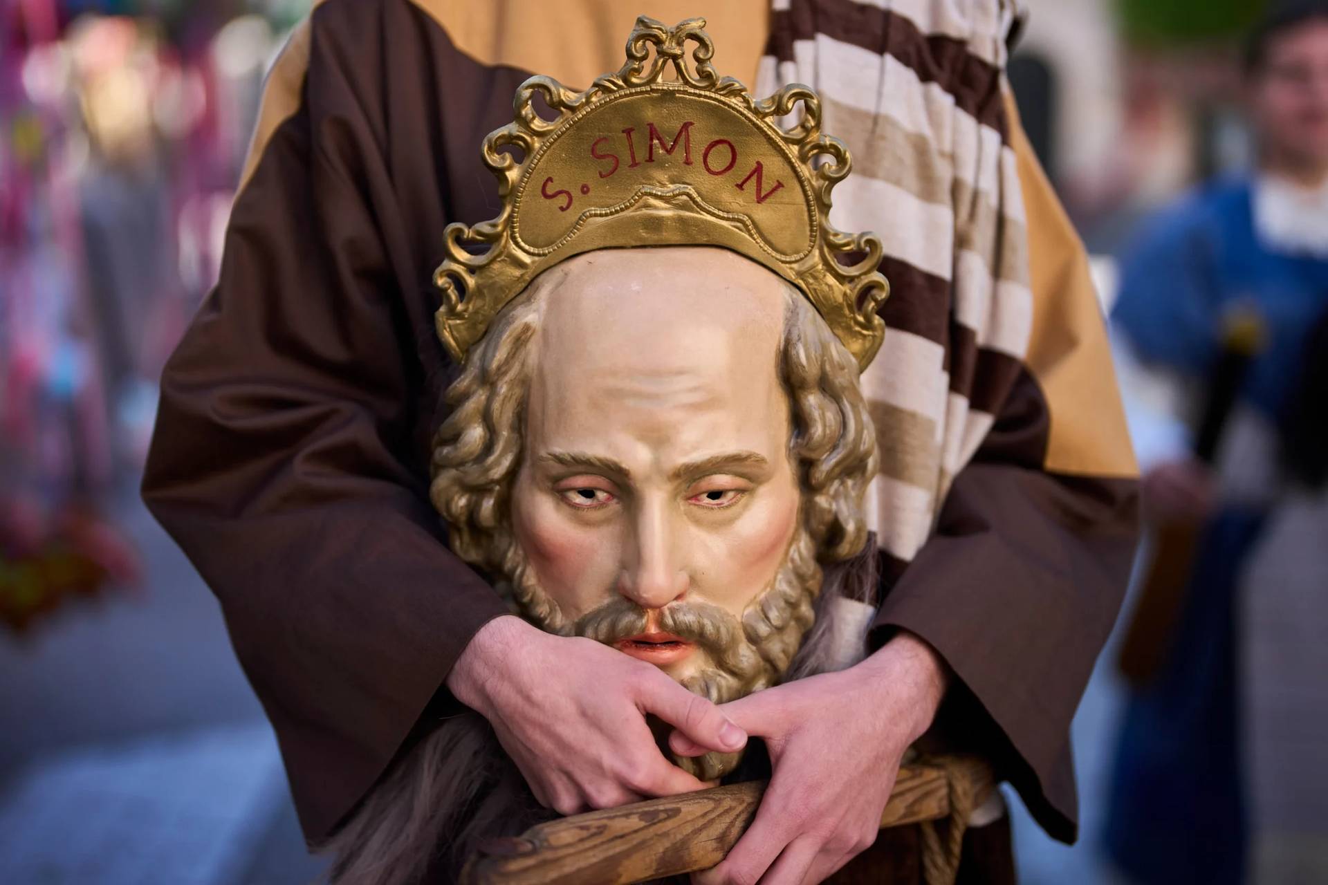 A penitent of the 'Pollinita' brotherhood, dressed in a typical Apostle costume, holds an image symbolizing the apostles during the Holy Week procession in Cabra, southern Spain, Sunday, March 29, 2026. (Credit: Manu Fernandez/AP.)