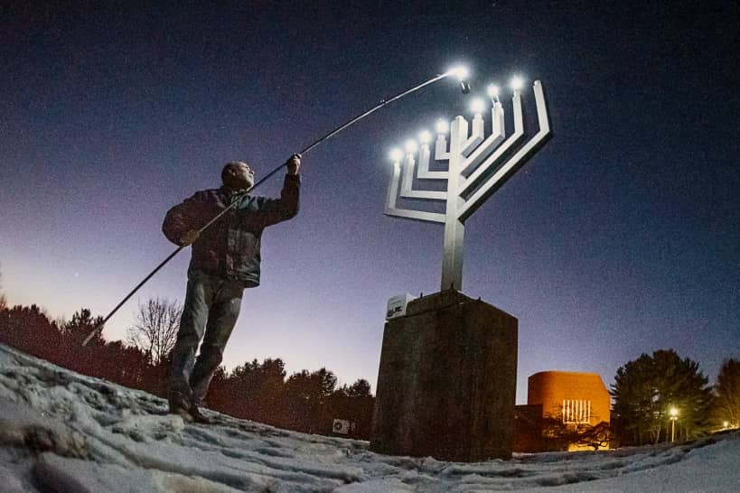 Joe Moscinski places the final light in the outdoor menorah at Temple Shalom, Dec. 20, 2019 in Auburn, Maine. (Credit: Andree/Sun Journal via AP.)