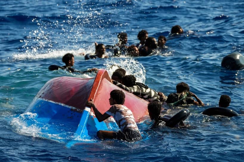 Migrants from Syria and Libya in a wooden boat call for help as they are assisted by Spanish NGO Open Arms during a rescue operation inside Malta’s SAR zone south of the Italian island of Lampedusa in the Mediterranean sea, Thursday, Aug. 11, 2022. (Credit: Francisco Seco/AP.)