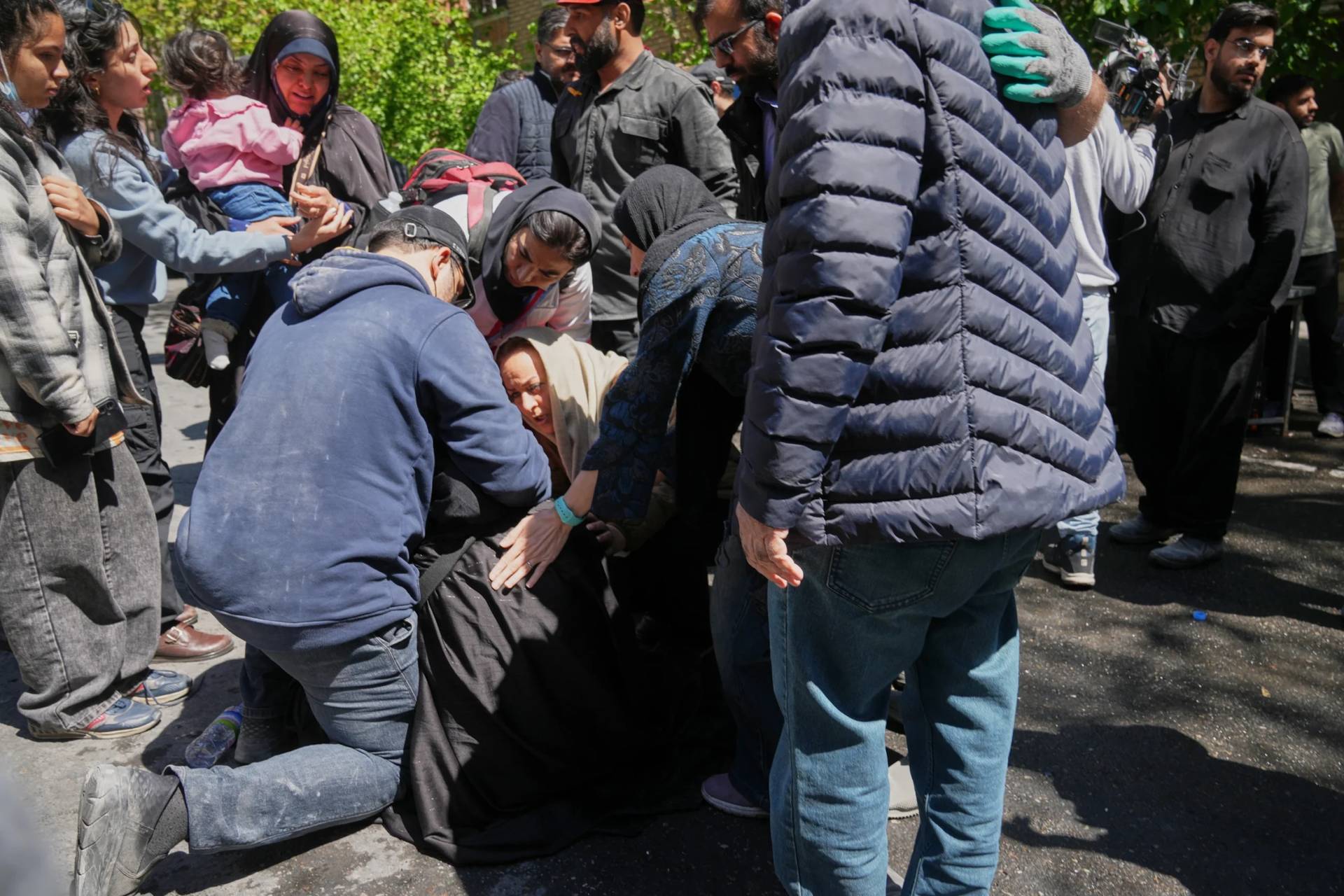 Bystanders try to comfort and assist a woman as she reacts near the site of a strike that, according to a security official at the scene, destroyed half of the Khorasaniha Synagogue and nearby residential buildings in Tehran, Iran, Tuesday, April 7, 2026. (Credit: Francisco Seco/AP.)