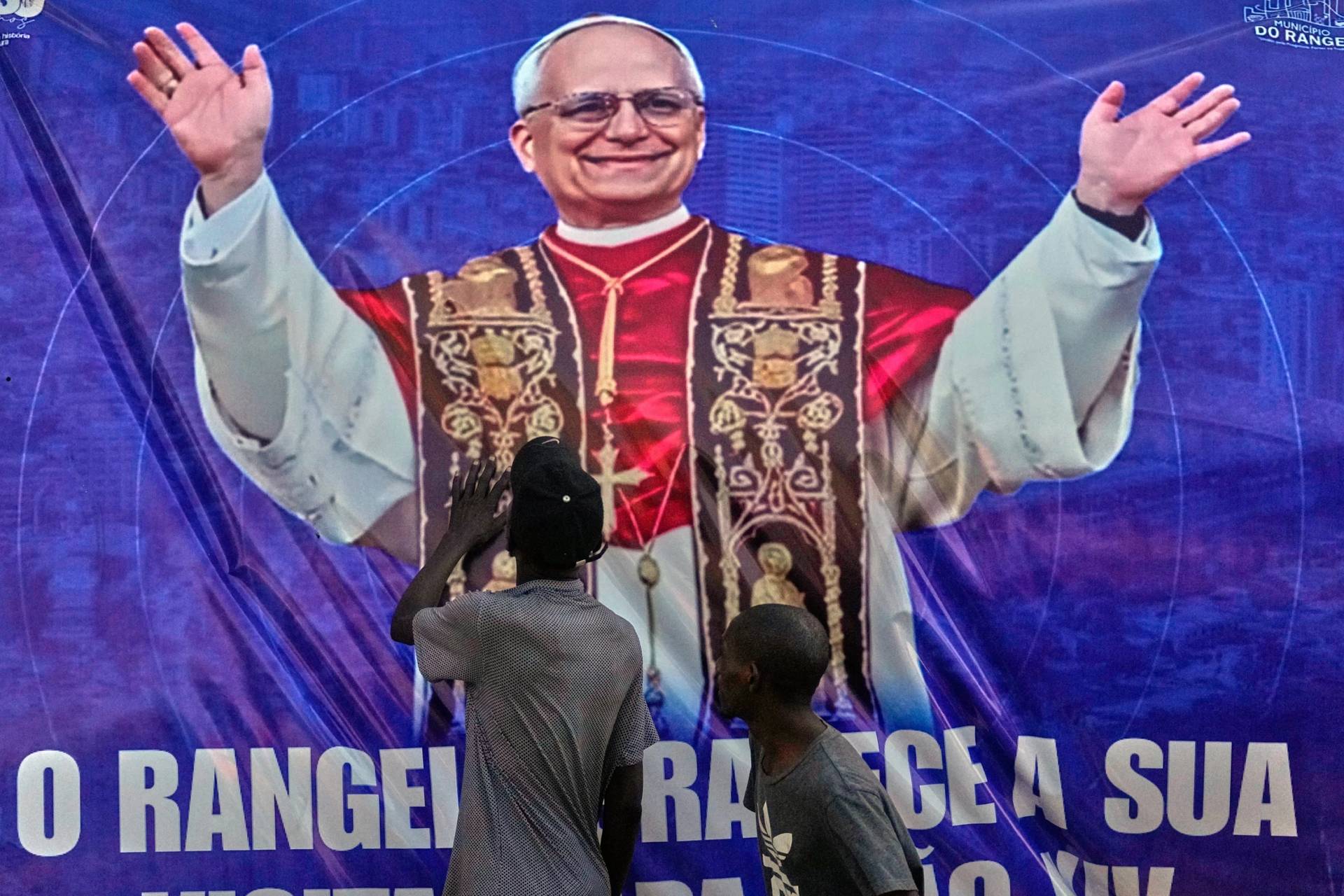 People touch a banner bearing an image of Pope Leo XIV in Luanda, Angola, Monday, April 20, 2026. (Credit: Themba Hadebe/AP.)