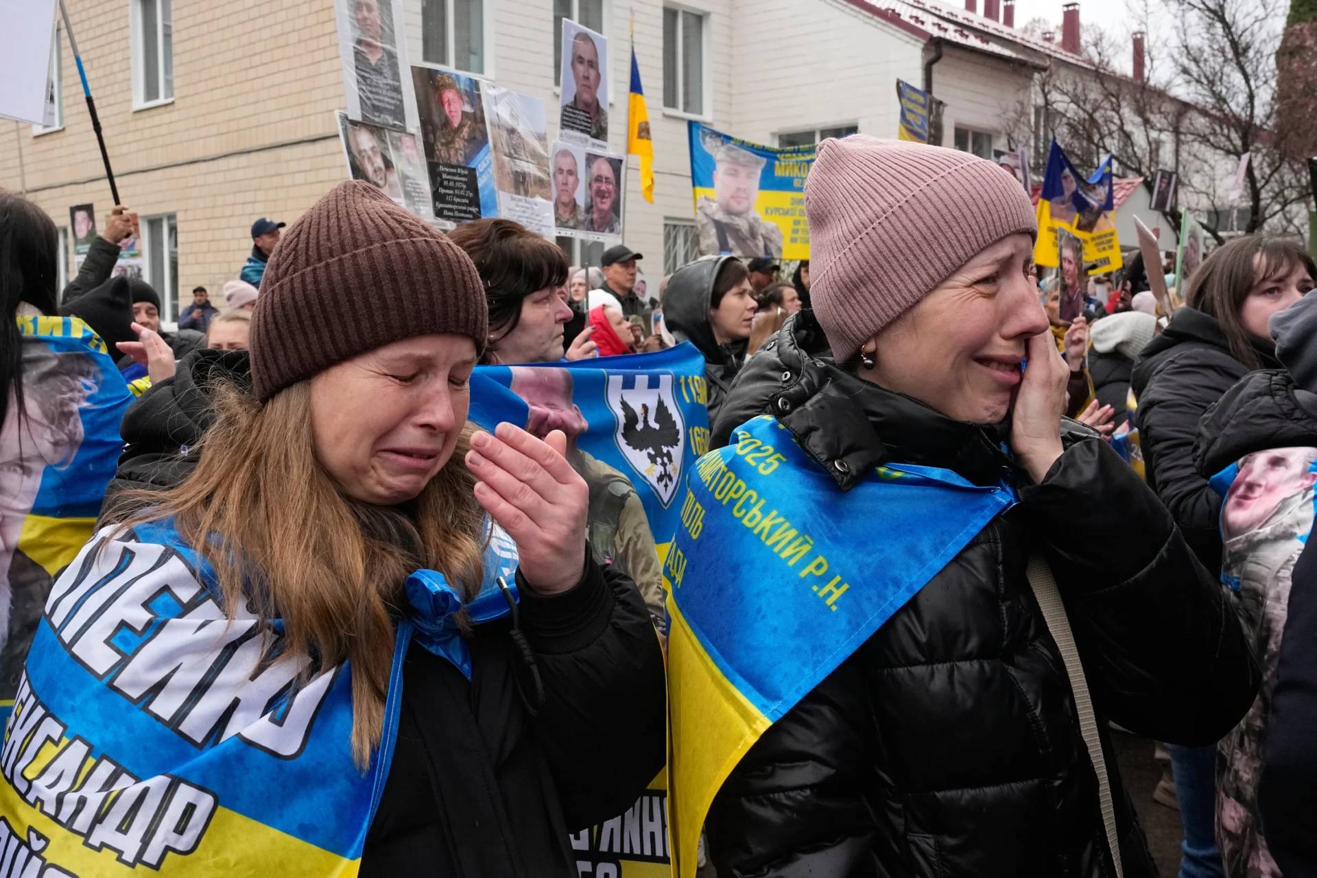 People cry as they hold hold photos of their missed relatives as Ukrainian soldiers return from captivity during a POW exchange between Russia and Ukraine in Chernyhiv region, Ukraine, Saturday, April 11, 2026. (Credit: Efrem Lukatsky/AP.)