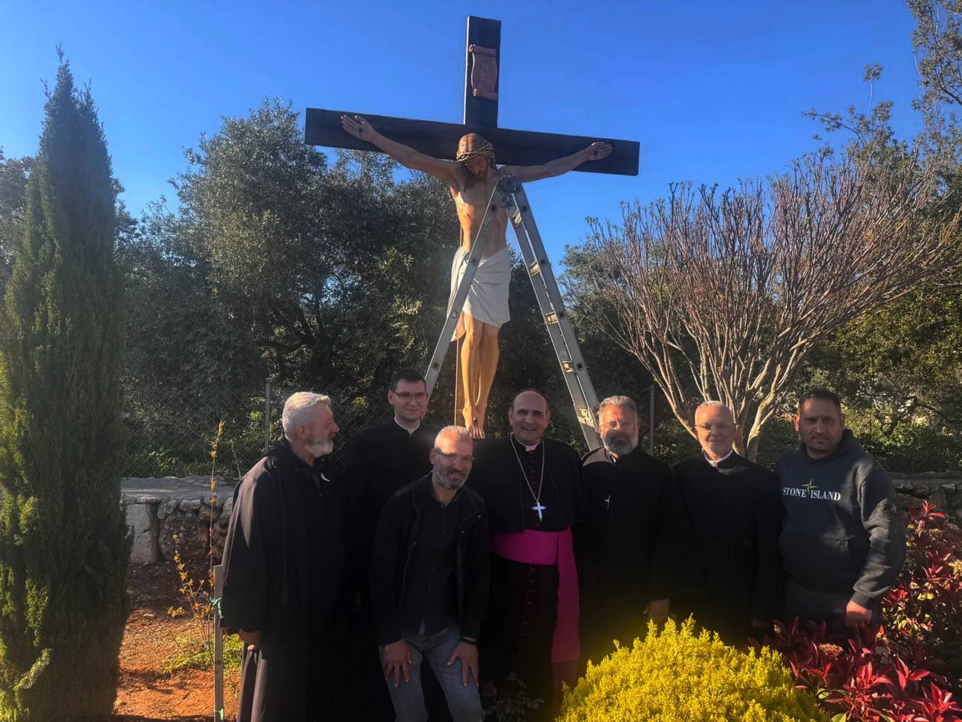 The Apostolic Nuncio to Lebanon Archbishop Paolo Borgia, center, poses with residents next to a crucifix sent by Italy to replace one that was defaced last week by an Israeli soldier in the Christian village of Debel, south Lebanon, Wednesday, April 22, 2026. (Credit: Houssam Naddaf via AP.)