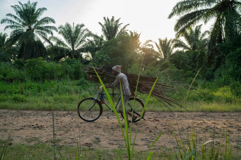 A man carries wood on his bicycle as he rides past a cemetery in Beni, Congo, Tuesday, July 16, 2019. (Credit: Jerome Delay/AP.)