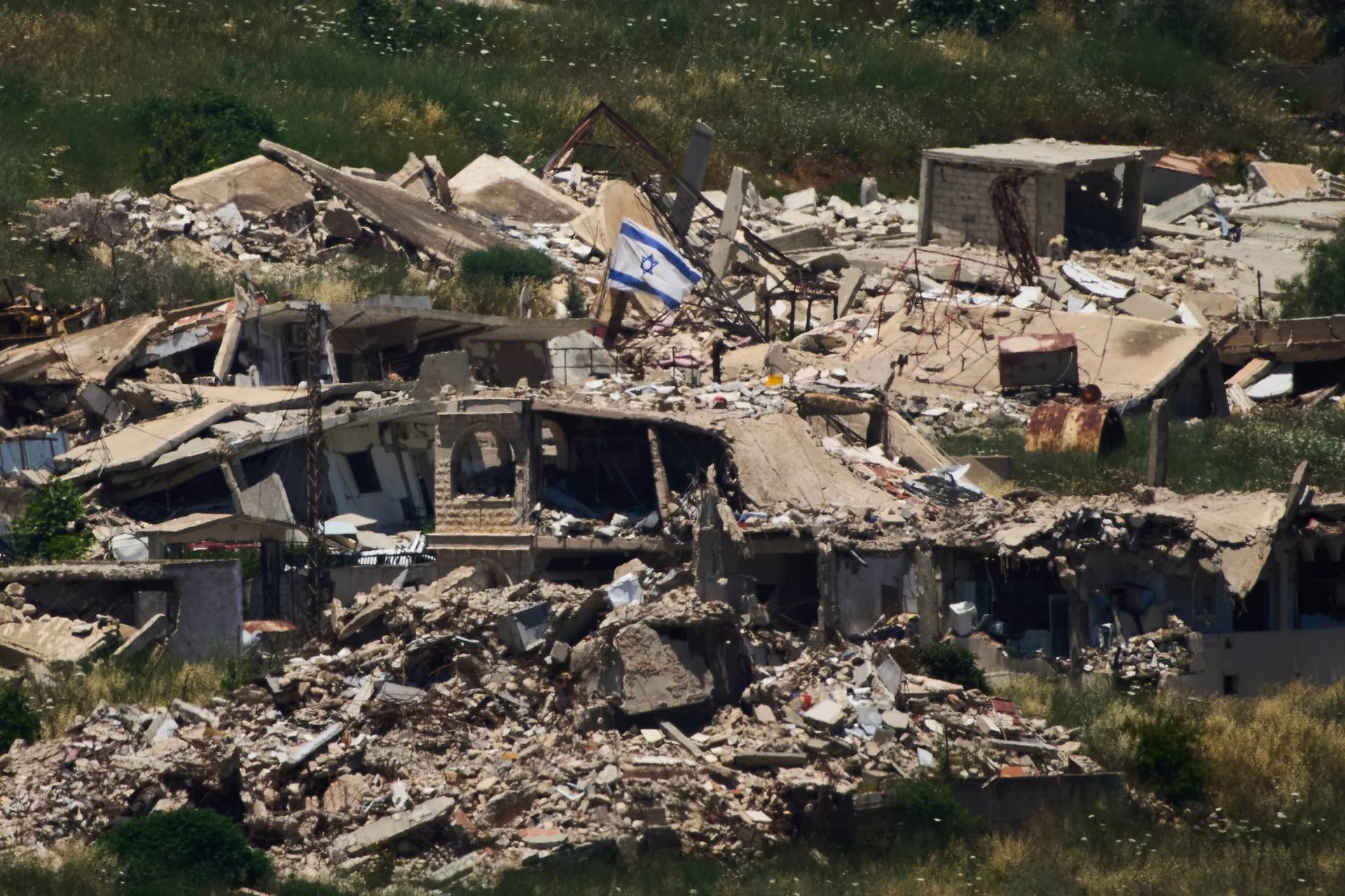 An Israeli flag hangs on a destroyed building in southern Lebanon as seen from northern Israel, Thursday June 4, 2026. (Credit: Ariel Schalit/AP.)