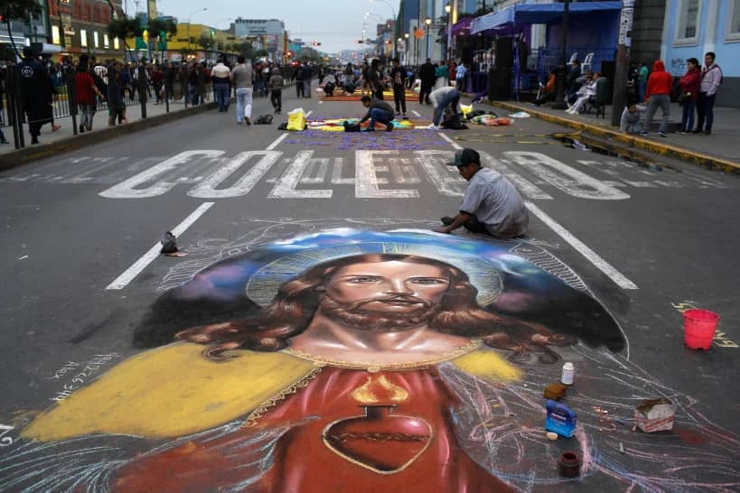 A man works on a chalk drawing depicting the Sacred Heart of Jesus, Oct. 28, 2017, in Lima, Peru. (Credit: Martin Mejia/AP.)