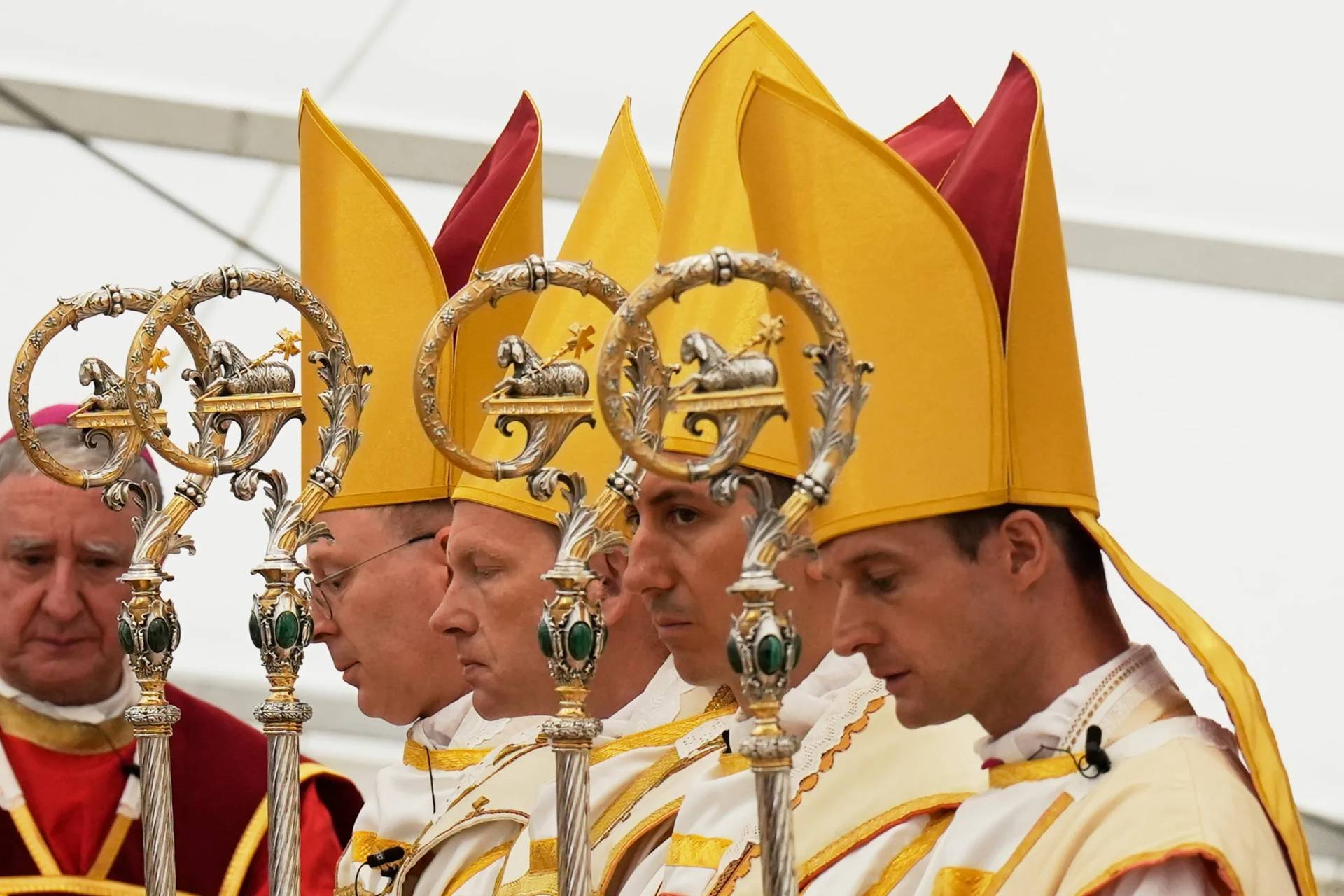 Newly consecrated bishops, from left, Pascal Schreiber, Michael Goldade, Michel Poinsinet de Sivry and Marc Hanappier, wearing their miters and holding their pastoral staffs, pray at the end of their consecration ceremony in a tent set up outside the Society of St. Pius X seminary in Econe, Switzerland, Wednesday, July 1, 2026. (Credit: Baz Ratner/AP.)
