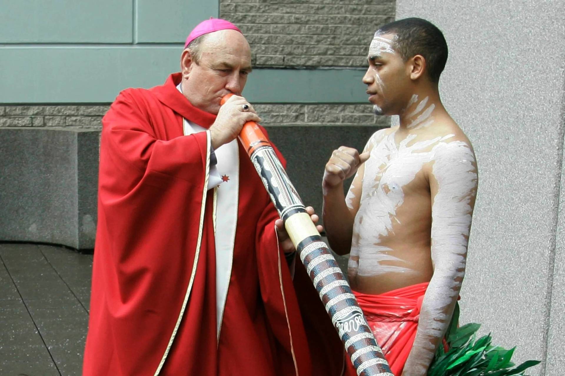 Bishop Christopher Saunders of Broome, left, tries to play a didgeridoo during a World Youth Day 2008 media event in Sydney, Australia, on April 17, 2008. (Credit: Rob Griffith/AP.)