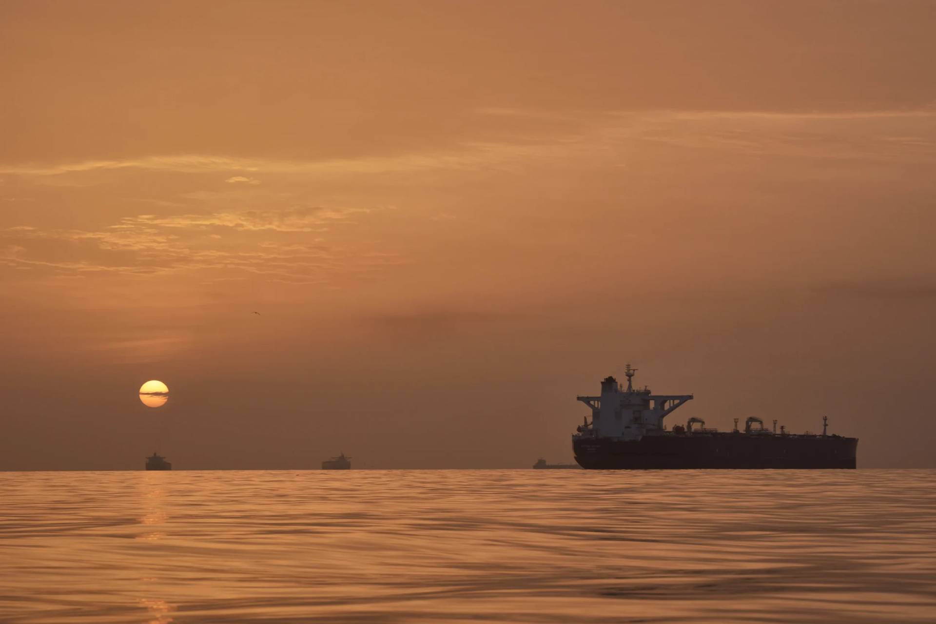 The sun rises behind tankers anchored in the Strait of Hormuz off the coast of Qeshm Island, Iran, Saturday, April 18, 2026. (Credit: Asghar Besharati/AP.)