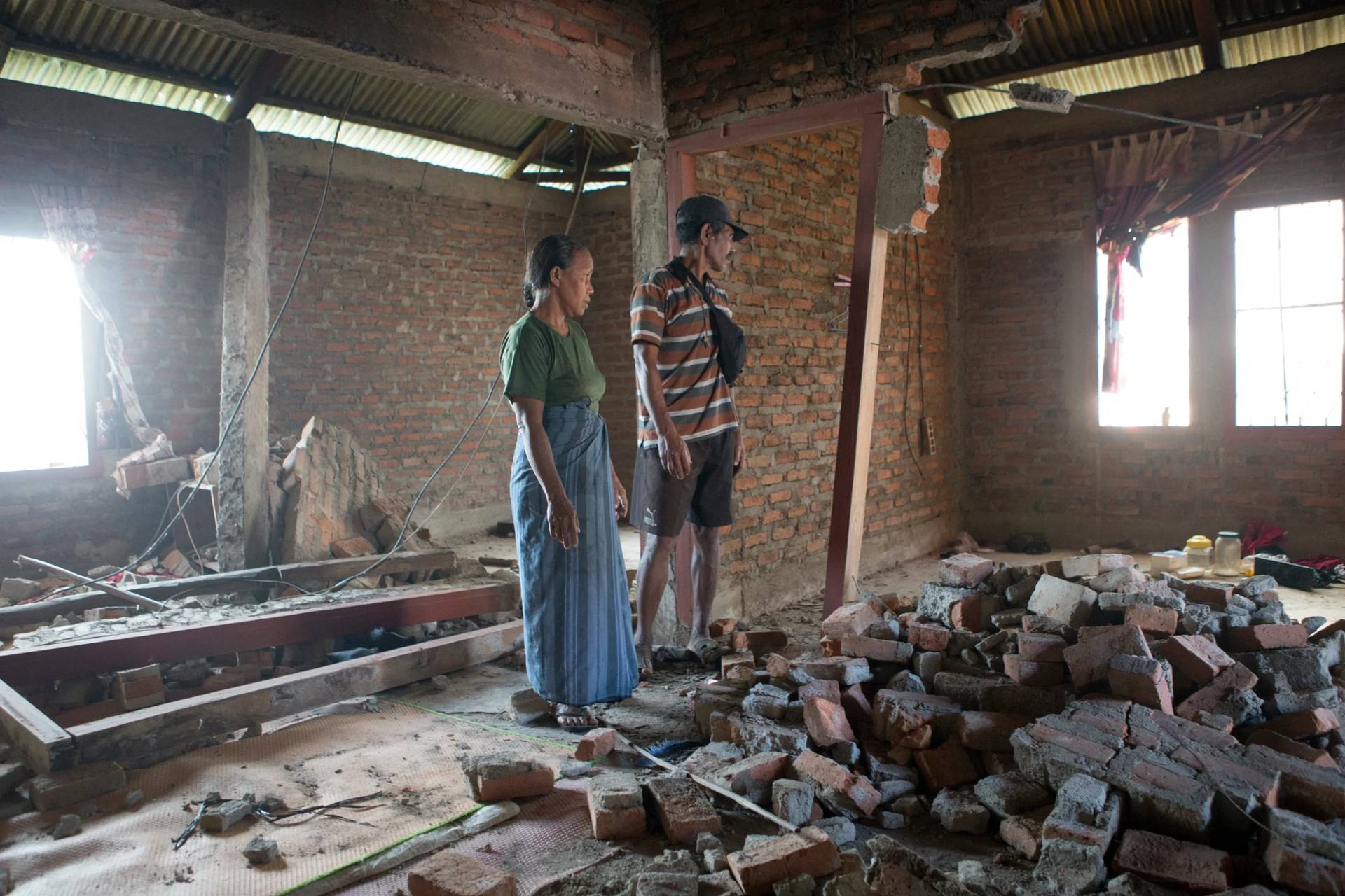 Stefanus Sailon, right, and his wife Sisilia Ilus inspect their house which was damaged during an earthquake in Mbeliling, East Nusa Tenggara province, Indonesia, Sunday, Aug. 16, 2026. (Credit: Firdia Lisnawati/AP.)