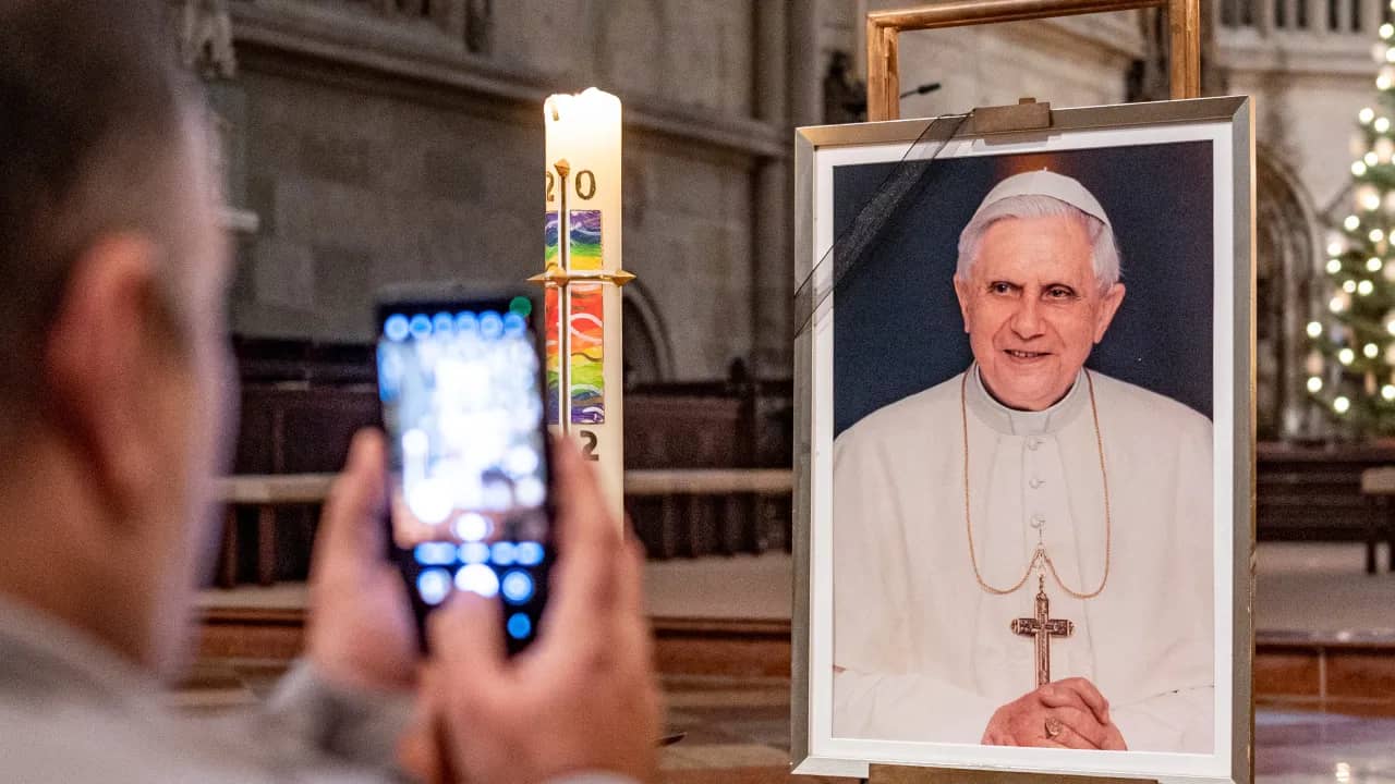 A person takes a picture of a portrait of Pope Emeritus Benedict XVI at St. Peter’s Cathedral in Regensburg, Germany, Saturday, Dec. 31, 2022. (Credit: Armin Weigl/dpa via AP.)