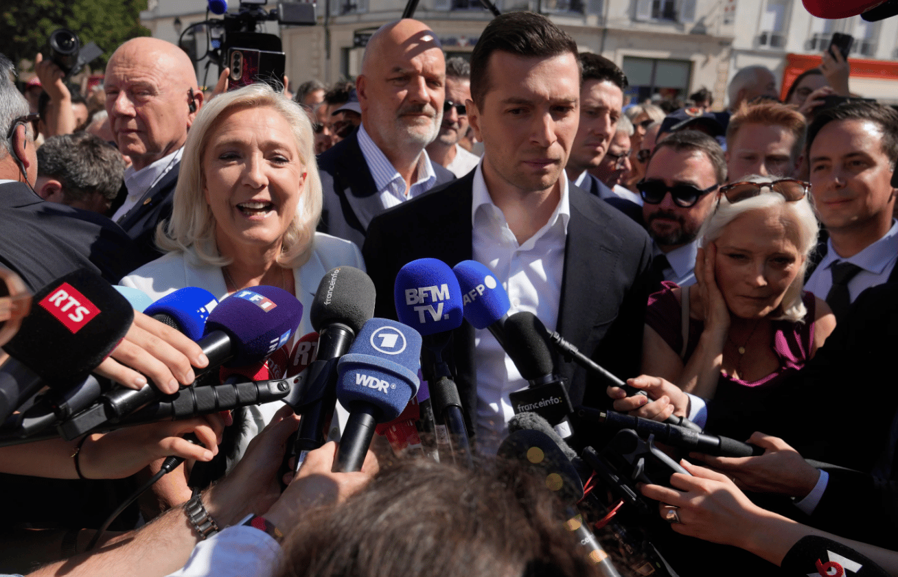 Rightwing leader Marine Le Pen and Far-right party National Rally president Jordan Bardella answer journalists as they arrive to visit a market in La Fleche, western France on July. 8, 2026. (Credit: Michel Euler/AP.)