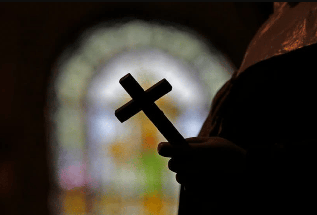A cross is silhouetted against a stained glass window inside a Catholic Church in New Orleans on Dec. 1, 2012. (Credit: Gerald Herbert/AP.)