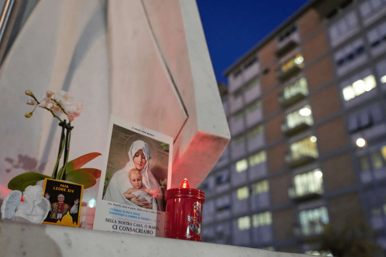 An image of Pope Leo XIV rests at the base of a statue of late pope St. John Paul II outside the Agostino Gemelli Polyclinic, where Leo is hospitalized for surgery to remove a lung nodule, in Rome, Tuesday, Oct. 13, 2026. (Credit: Gregorio Borgia/AP.)